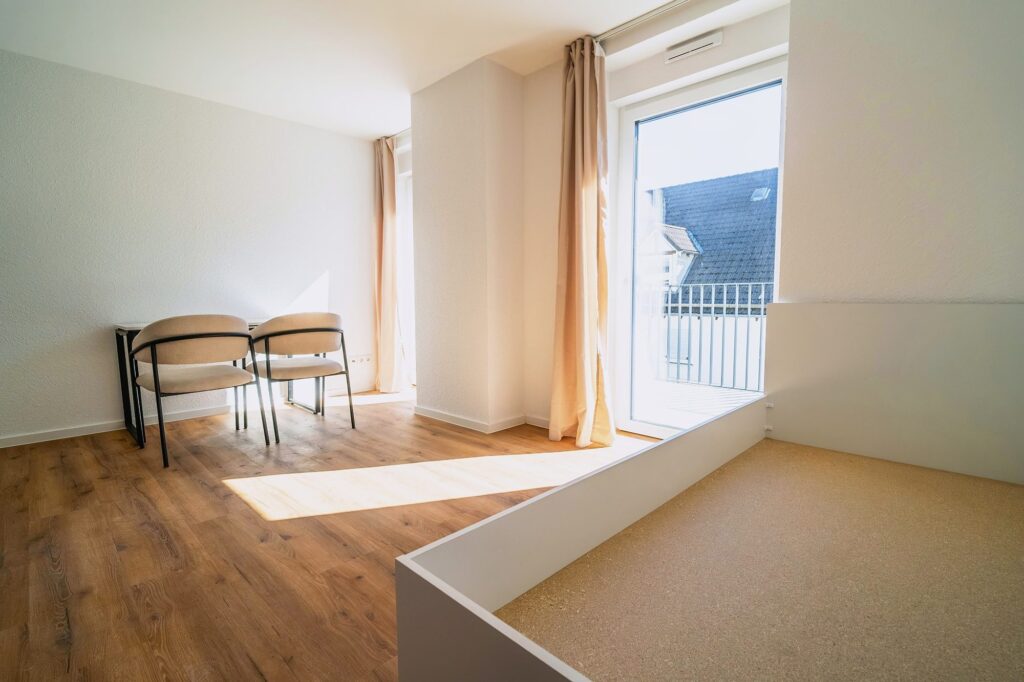 Heller Wohnbereich mit Schreibtisch, Stühlen und großem Fenster