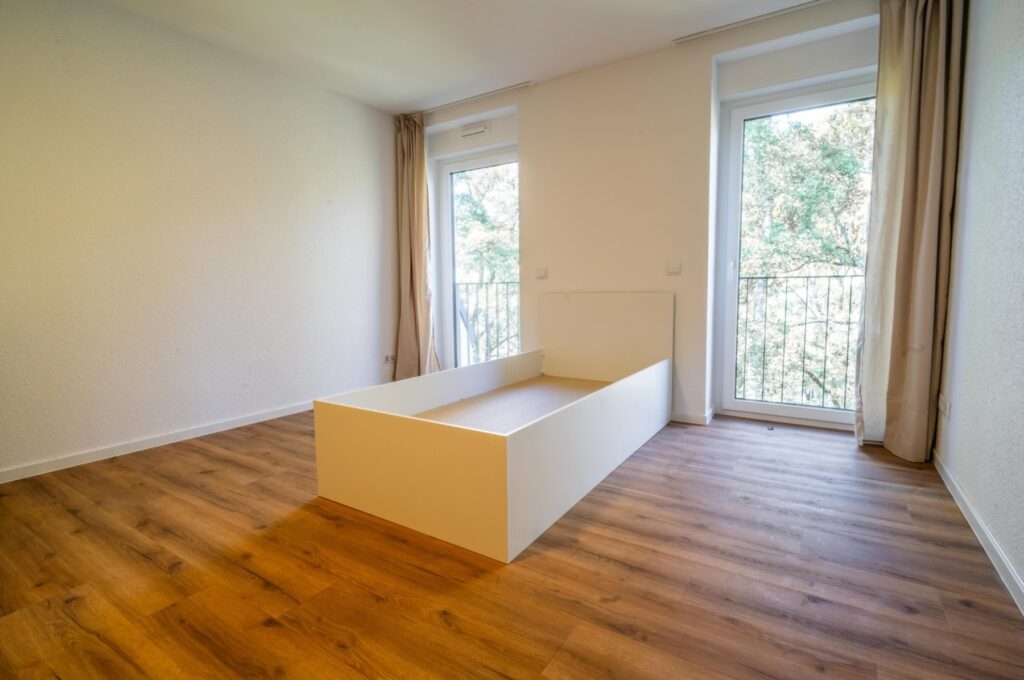 Schlafzimmer mit Fenster und Balkontür im aktuellen Zustand (echtes Foto)